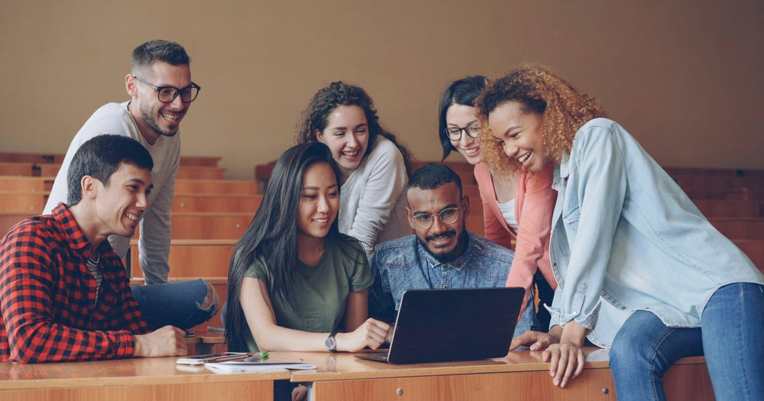 Grupo de estudiantes universitarios mirando un portátil en clase
