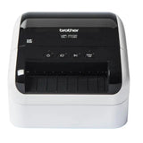 Impresora térmica Brother QL-1100C para etiquetas, vista frontal con papel de etiquetas en proceso de impresión.
